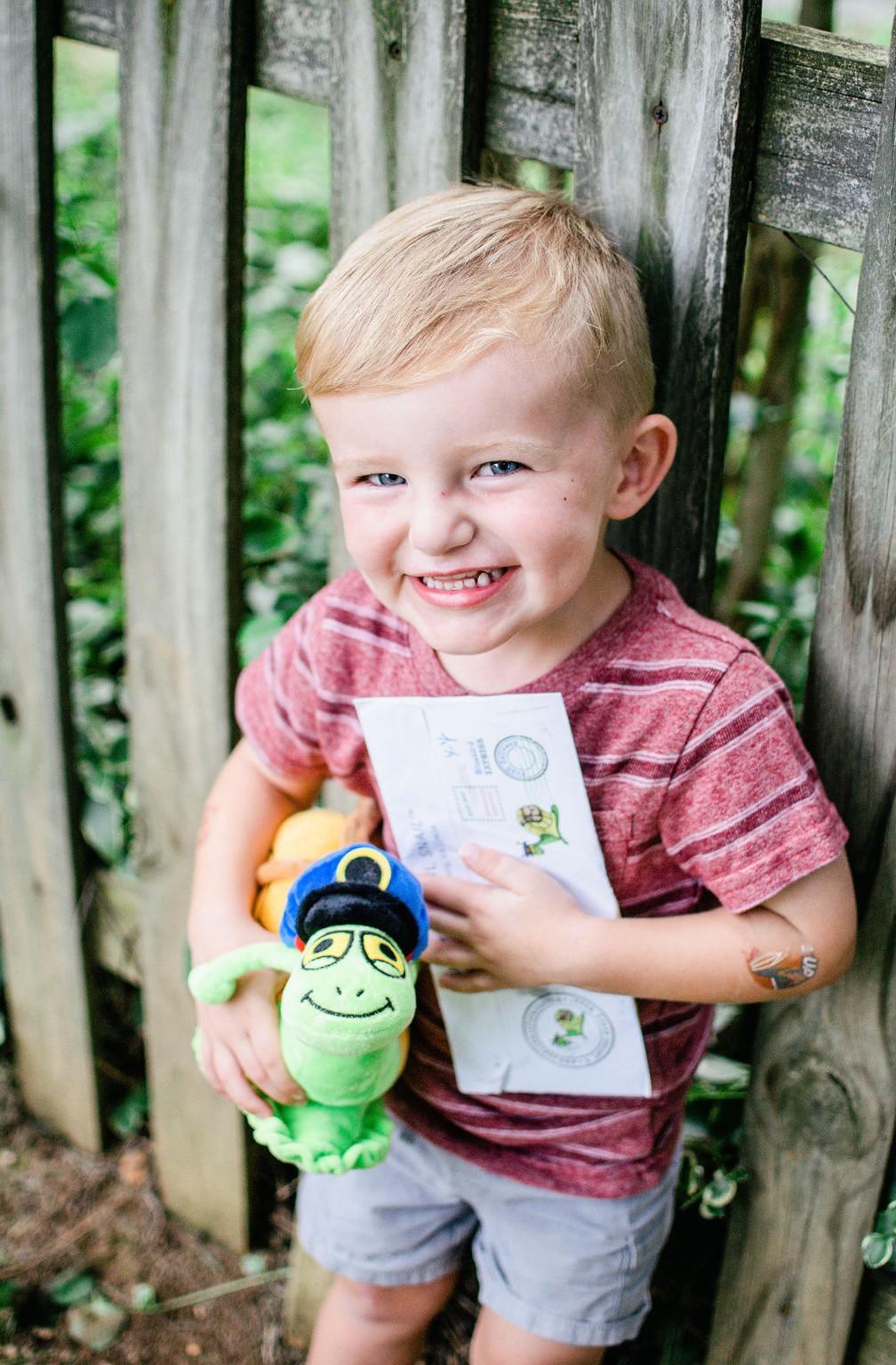 A smiling boy holding his plush snail